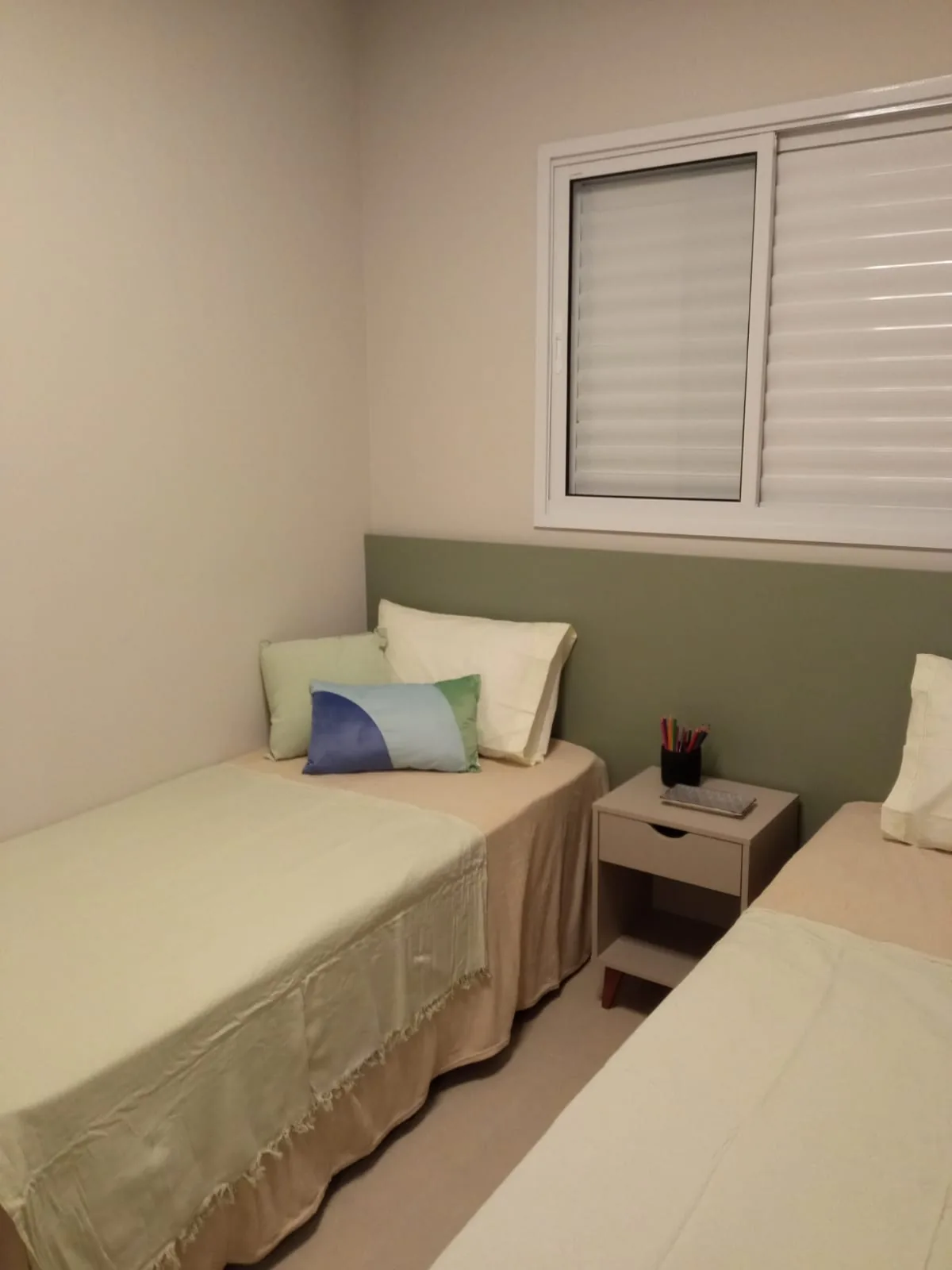 Quarto de solteiro com painel verde-sálvia e roupa de cama em pistache